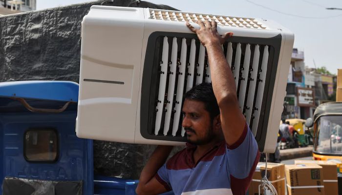 একজন কর্মী গ্রাহকের জন্য একটি এয়ার কুলার বহন করে নিয়ে যাচ্ছেন। বৃহস্পতিবার ভারতের আহমেদাবাদে। ছবি : রয়টার্স