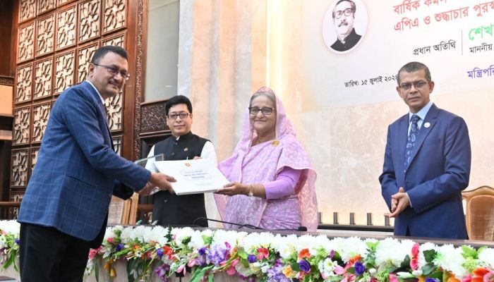 প্রধানমন্ত্রী শেখ হাসিনার কাছ থেকে পুরস্কার বুঝে নিচ্ছেন শ্রম ও কর্মসংস্থান মন্ত্রণালয়ের সচিব মাহবুব হোসেন। প্রবা ফটো