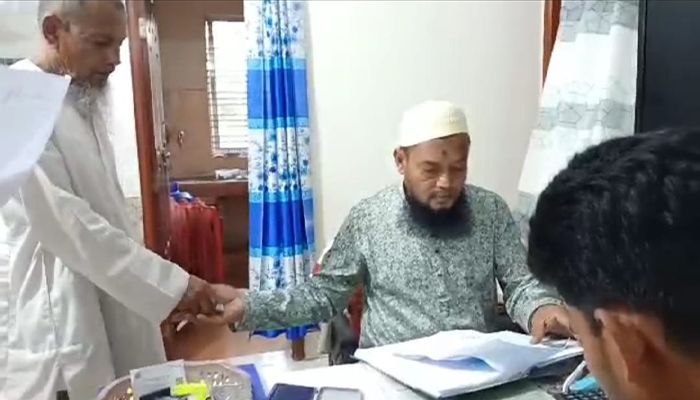 ছবিতে এক কৃষকের কাছ থেকে টাকা নিচ্ছেন অফিস সহায়ক এনামুল হক। সম্প্রতি তোলা