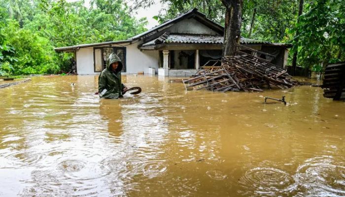 কলম্বোর উপকণ্ঠে কাদুওয়েলায় ভারী বৃষ্টিপাতের পর একজন ব্যক্তি তার বাড়ির বাইরে বন্যার জলের মধ্য দিয়ে হেঁটে যাচ্ছেন।