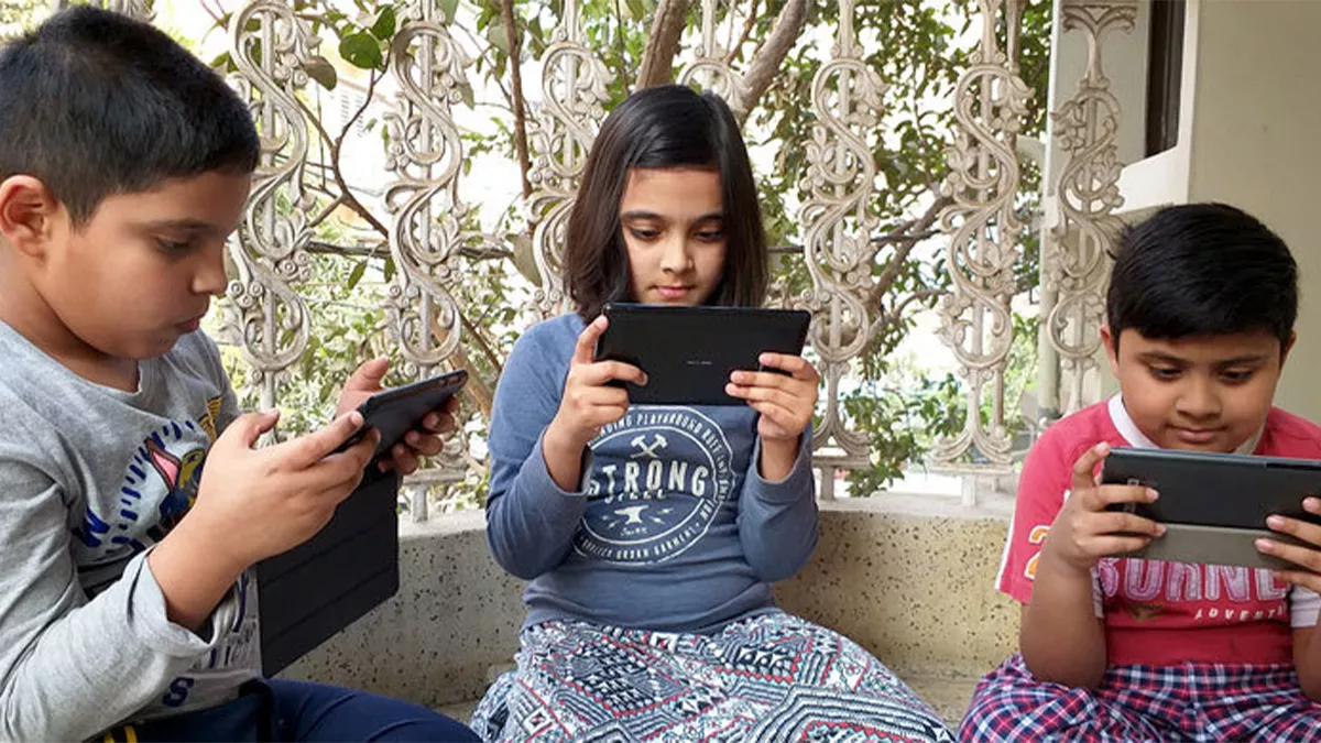 তিন শিশুর মোবাইল ফোনে গেম খেলার দৃশ্য।