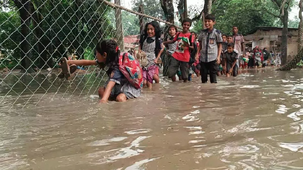 প্রতিদিন হাঁটুজল পেরিয়ে, ব্যাগ মাথায় তুলে কিংবা কাঁধে ঝুলিয়ে এবং জুতা হাতে নিয়ে স্কুলে যেতে হচ্ছে শিক্ষার্থীদেরকে। ছবি: প্রতিদিনের বাংলাদেশ